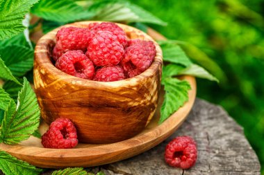 Tahta kasede taze sulu ahududu. Eski ahşap bir masanın üzerinde ahudududularla dolu bir yaz. Uzayı kopyala. Ahududu reçeli kavanozu ve ahşap arka planda taze böğürtlen.