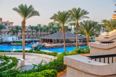 Hurghada, Egypt. Egyptian garden with palm trees in hotel .Swimming pool and accommodation at tropical resort. Buildings, swimming pools and a recreation area by the red sea. All iclusive holidays.