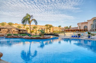 Hurghada, Egypt. Egyptian garden with palm trees in hotel .Swimming pool and accommodation at tropical resort. Buildings, swimming pools and a recreation area by the red sea. All iclusive holidays.
