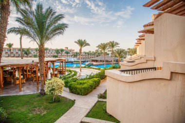 Hurghada, Egypt. Egyptian garden with palm trees in hotel .Swimming pool and accommodation at tropical resort. Buildings, swimming pools and a recreation area by the red sea. All iclusive holidays.