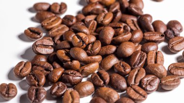 Beyaz arkaplanda paket tasarımı elementleri olarak izole edilmiş taze kahve çekirdekleri yığını.