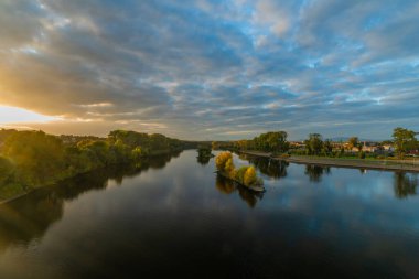 Roudnice Nad Labem kasabasında eski kilisesi ve Labe nehri kuleleri olan turuncu gün batımı.
