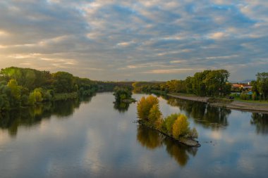 Roudnice Nad Labem kasabasında eski kilisesi ve Labe nehri kuleleri olan turuncu gün batımı.