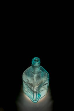 Taze ışık ve siyah arka planı olan eski renkli kirli cam şişe.