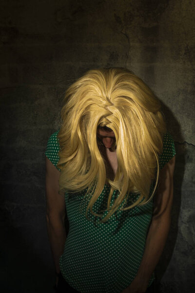 Blond hair young woman near old stone dark wall