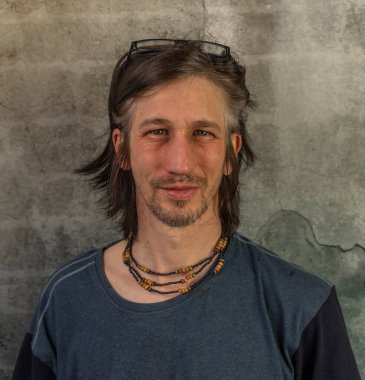 Sakallı adam portresi, eski renkli taş duvarın yanında.