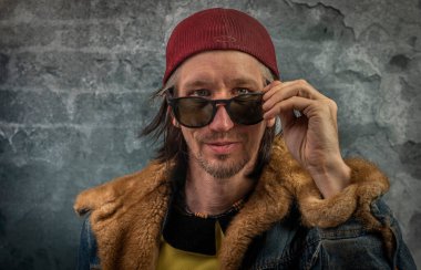 Sakallı adam portresi, eski renkli taş duvarın yanında.