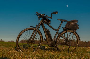 Güney Bohemya 'daki Ceske Budejovice şehrinin üzerinde gün batımı ışığı olan siyah bir bisiklet.