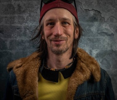 Sakallı adam portresi, eski renkli taş duvarın yanında.