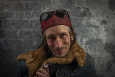 Sakallı adam portresi, eski renkli taş duvarın yanında.