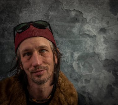 Sakallı adam portresi, eski renkli taş duvarın yanında.