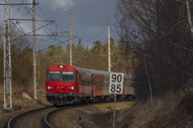 Kırmızı yolcu Avusturya Velesin İstasyonu 'nda kış günü soğuk bir günde tren çalışır.