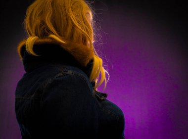 Sarı saçlı, menekşe rengi arka planda bir kadın.