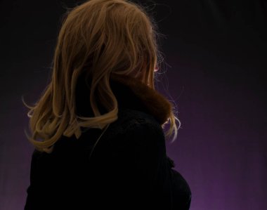 Sarı saçlı, menekşe rengi arka planda bir kadın.