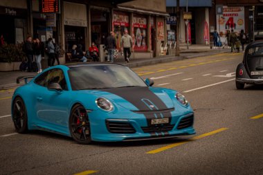 Baharda güneşli bir günde İsviçre Locarno şehrinin modern caddesinde mavi bir araba.