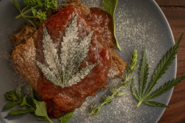 Şeker erikli marihuana ezmeli kek ve mavi tabakta şifalı otlar ve ahşap masa.