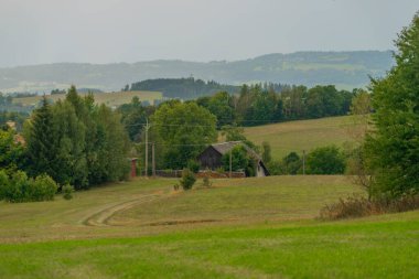 Yaprak ağaçları ve bulutlu gri gökyüzü olan Roprachtice köyünün manzarası