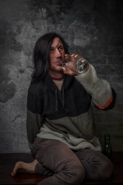 Eski tuğla duvarın yanında bir şişe alkollü siyah saçlı adam.