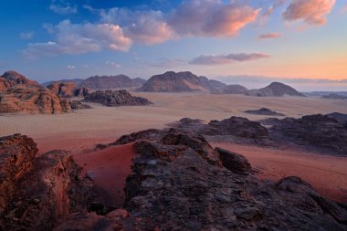 Wadi Rum Çölü, taşlı ve taşlı kırmızı kum. Doğada akşam pembe menekşe gün batımı. Ürdün 'e seyahat, Arabistan doğası. Ürdün dağ manzarası.