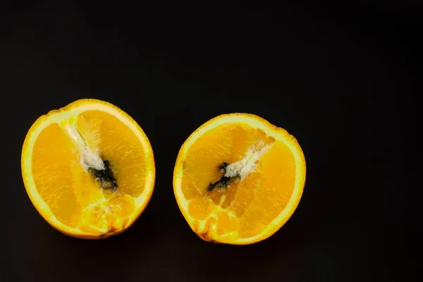 Black rot in citrus. Sliced oranges on a black background. Storage and transportation of fruits for supermarkets.Alternaria diseases of citrus