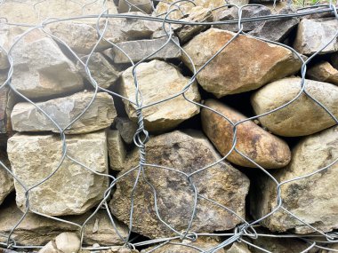 Gabions, a spatial mesh structure filled with bulk materials. Coastal fortifications. Landscaping and fortification. Stones in the grid.