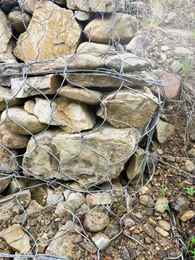 Gabions, a spatial mesh structure filled with bulk materials. Coastal fortifications. Landscaping and fortification. Stones in the grid.