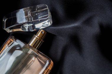 Siyah arka planda bir şişe parfümü kapat. Üst görünüm zarif, lakonik kompozisyon. Eau de Tuvalet ve fotokopi alanı ile açık kapak.