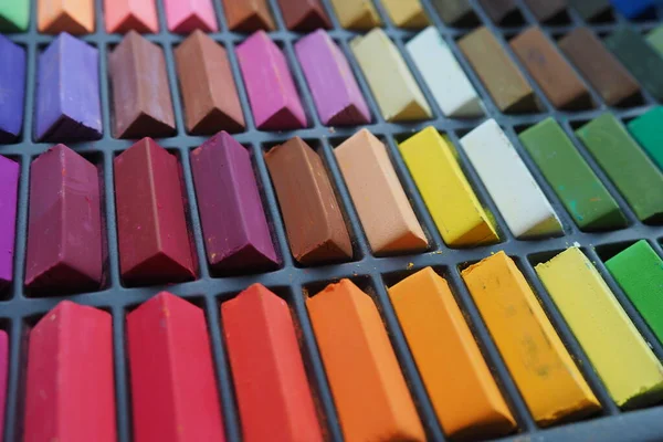 Üstteki renkli pastel renkler siyah bir kutunun içinde serili. Yaratıcılık, çizim ve sanat dersleri konsepti. Okulda çocuklara ders vermek için kırtasiye malzemesi