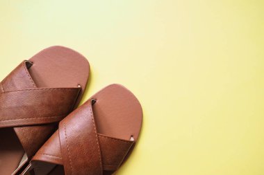 Üst manzara kahverengi deri ayakkabılar, kadınlar için sandaletler ve kopya alanı olan sarı arka plan.