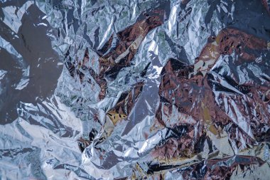 Gümüş folyodan yapılmış arka plan, hediyeler için paketleme, çiçekler. Parlak, yeni yıl tatili, uzay, fütüristik kompozisyonlar için arka plan