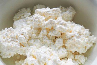 Beyaz kâse içinde iştah açıcı süzme peynirin kapağı. Süt ürünleri, peynirli kekler..