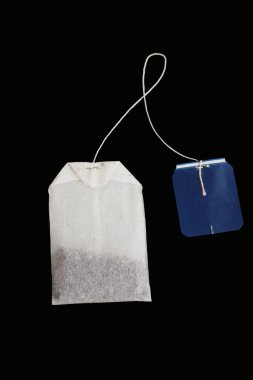 Rectangular tea bag with blue label isolated on black. Mockup, detail for creating marketing compositions in the theme of tea party, food products