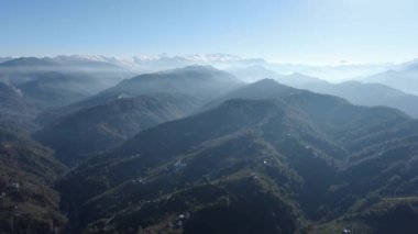 Türkiye 'nin kuzeyindeki Trabzon' da yağmur mevsiminde yemyeşil yağmur bulutları içindeki bir köyün havadan görünüşü yağmur ormanları dağını örtüyor    