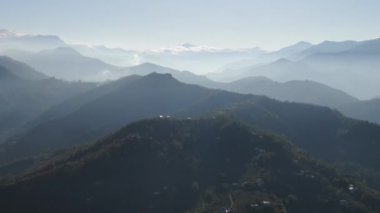 Türkiye 'nin kuzeyindeki Trabzon' da yağmur mevsiminde yemyeşil yağmur bulutları içindeki bir köyün havadan görünüşü yağmur ormanları dağını örtüyor    