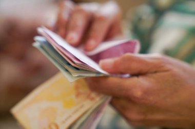 Kırışık ellerin Türk lira banknotlarını tuttuğu yakın plan.  