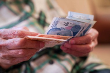 Kırışık ellerin Türk lira banknotlarını tuttuğu yakın plan.  