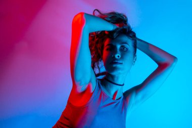 Renkli parlak neon ışıklarıyla stüdyoda poz veren yüksek model kadın. Parlak makyajlı güzel bir kadının portresi. Sanat tasarımı canlı biçimi