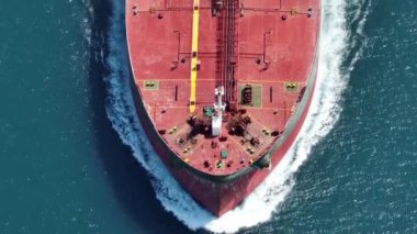 Aerial view of a heavy loaded container cargo vessel traveling over calm, blue sea