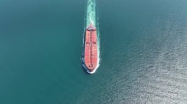 Aerial view of a heavy loaded container cargo vessel traveling over calm, blue sea