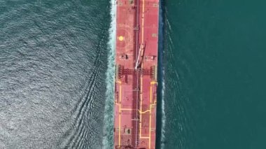 Aerial view of a heavy loaded container cargo vessel traveling over calm, blue sea