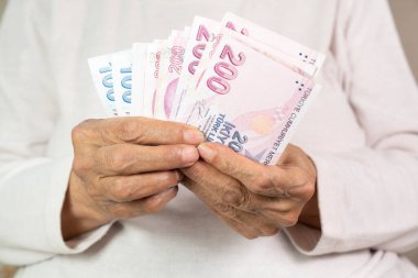 old woman holding some one hundred and two hundred cash banknotes, Close up clipart