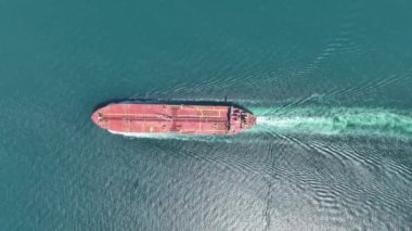 Aerial top down view at a bow of a container cargo ship traveling in full speed over blue ocean