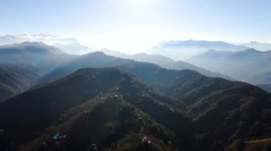 Türkiye 'nin kuzeyindeki Trabzon' da yağmur mevsiminde yemyeşil yağmur bulutları içindeki bir köyün havadan görünüşü yağmur ormanları dağını örtüyor    