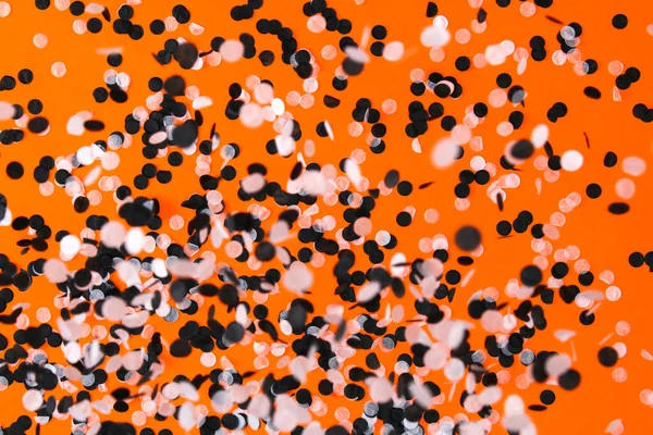 Blanco confeti negro volando fondo naranja. Fiesta de Halloween. — Foto de Stock