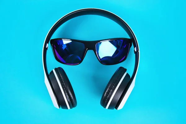 Zonnebril in witte draadloze hoofdtelefoon op blauwe achtergrond. Het concept van rust, ontspanning. — Stockfoto