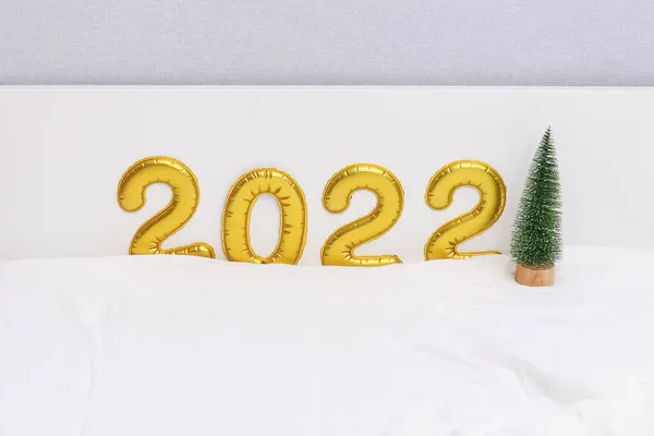 Номер 2022 написаний з повітряними кулями, фольгою на повітряній кулі, золотим, білим фоном, маленьким зеленим різдвом — стокове фото