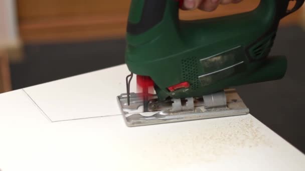 A man cuts a window sill from board for a window using an electric jigsaw for work. — Stock Video