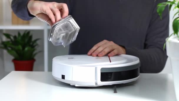 Muž vloží filtr a nádobu na zachycování prachu a trosek do vysavače robotů. — Stock video