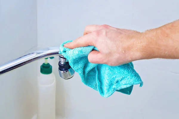 한 남자가 믹서 수돗물을 붓고, 수도 꼭지를 헝겊으로 닦는다. 집안 청소, 화장실. — 스톡 사진
