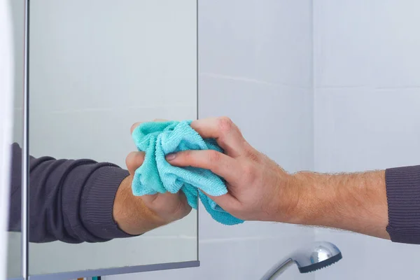 화장실에서 거울 캐비닛을 헝겊으로 닦는 남자. 집안 청소, 화장실. — 스톡 사진
